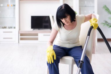 Yaşlı kadın elektrik süpürgesinden yorgun düştü.