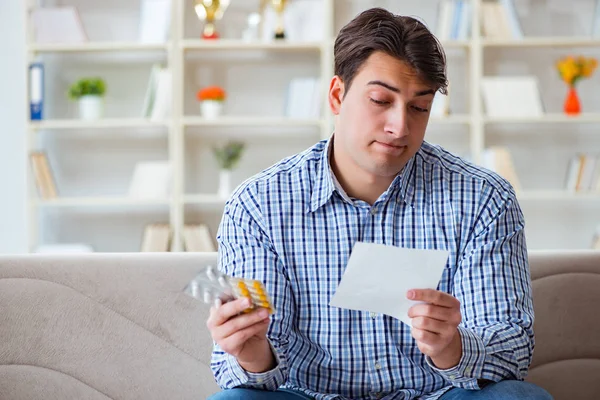 Kanepede ilaç ve reçeteyle oturan genç adam. 