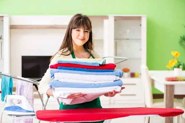 Jeune femme repassage vêtements à la maison — Photo