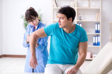 Doktor çekiçle sinir reflekslerini kontrol ediyor