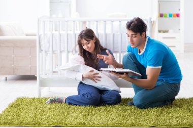 Yeni doğmuş bebekleriyle halıda oturan genç ebeveynler. 