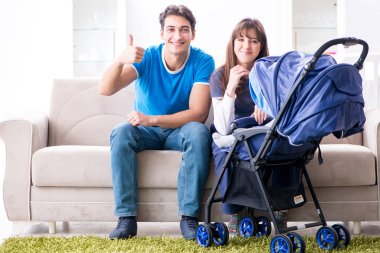 Bebekleri bebek arabasında oturan genç ebeveynler.