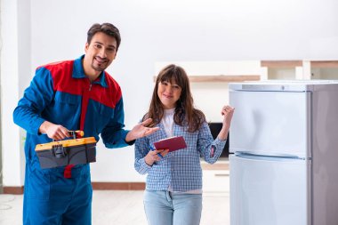 Adam müşteriyle buzdolabını tamir ediyor.