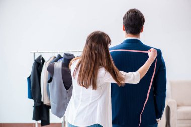 Profesyonel terzi resmi kıyafet için ölçü alıyor.