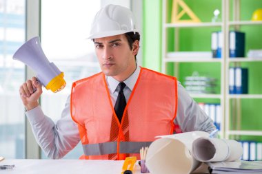 Ofiste hoparlörlü inşaat yöneticisi oturuyor. 