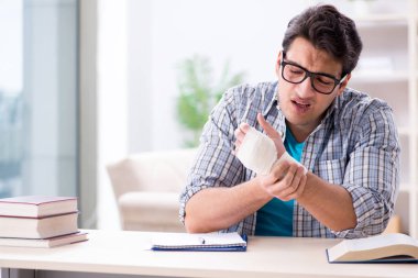 Eli yaralı genç bir öğrenci sınavlara hazırlanıyor. 