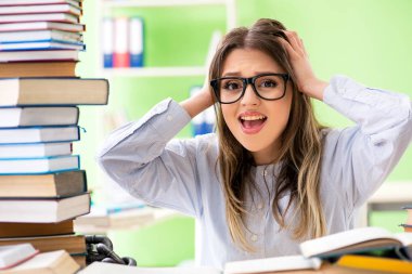 Sınavlara bir sürü kitapla hazırlanan genç kız öğrenci. 