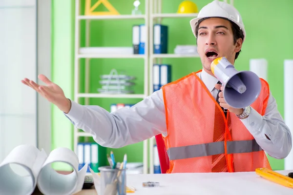 Construction supervisor with loudspeaker sitting in the office — Stock Photo, Image