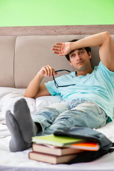 Student bereidt zich voor op examens thuis in slaapkamer liggend op het bed — Stockfoto