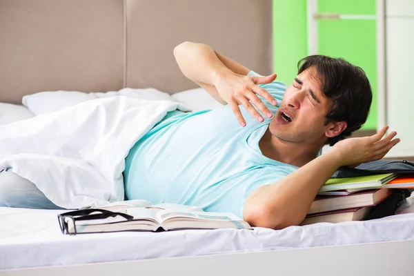 Studerande förbereder sig för tentamen hemma i sovrummet liggande på sängen — Stockfoto