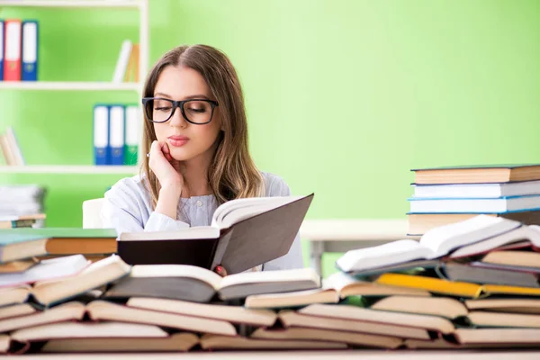 Jonge vrouwelijke student bereidt zich voor op examens met veel boeken — Stockfoto