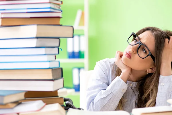 Jonge vrouwelijke student bereidt zich voor op examens met veel boeken — Stockfoto