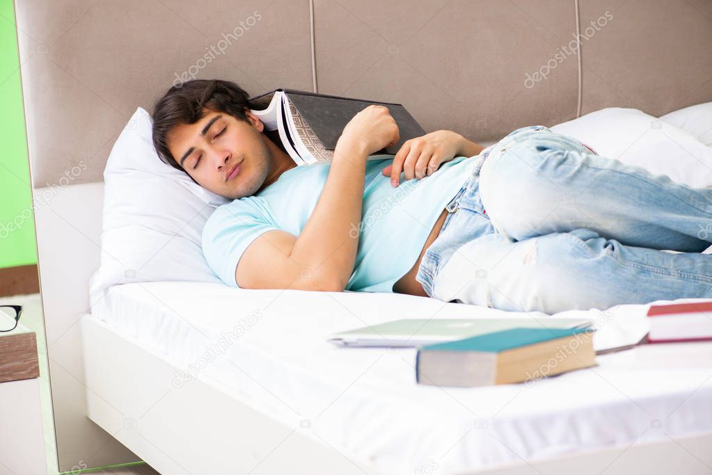 Student preparing for exams at home in bedroom lying on the bed