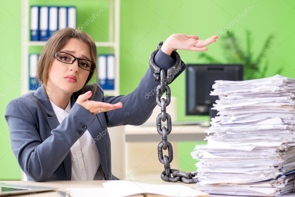 Young female employee  busy with ongoing paperwork chained to th