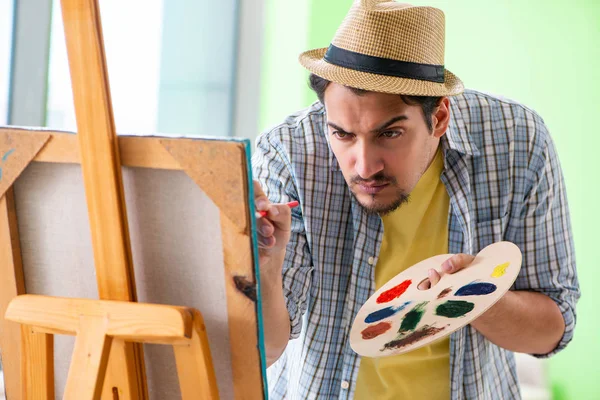 Joven artista masculino trabajando en una nueva pintura en su estudio — Foto de Stock