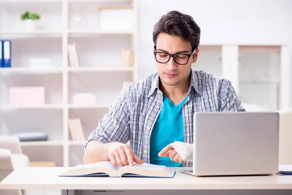 Junger Student mit Handverletzung bereitet sich auf die Prüfungen vor — Stockfoto