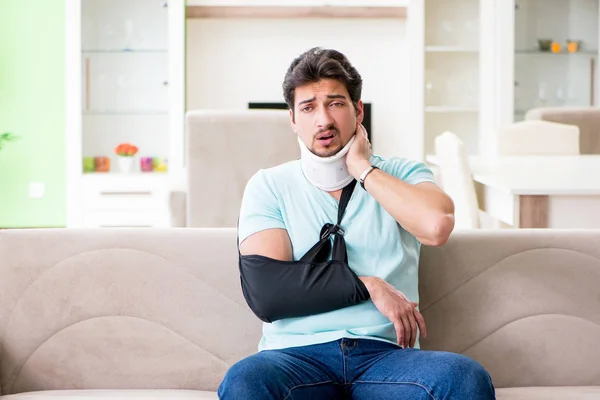 Joven estudiante con lesión en el cuello y la mano sentado en el sofá — Foto de Stock