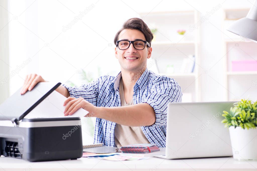 Young man employee working at copying machine in the office 