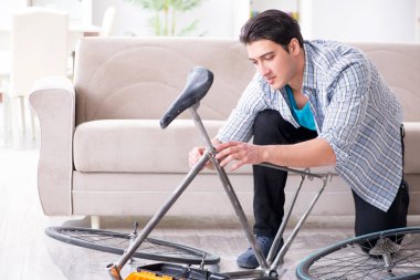 Evde bisiklet tamir eden genç bir adam.