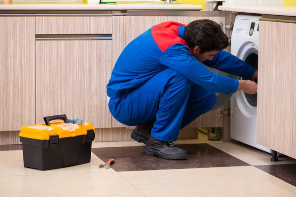 Repairman repairing washing machine in the kitchen — Stock Photo, Image