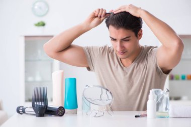 Genç yakışıklı adam aynaya bakıyor. 