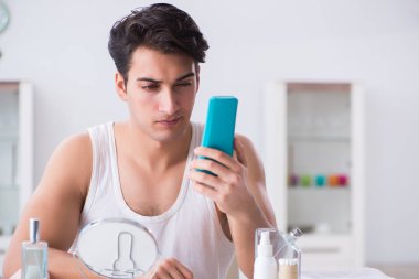 Genç yakışıklı adam aynaya bakıyor. 