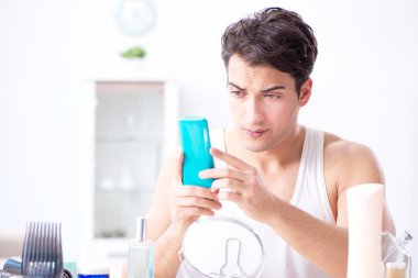 Genç yakışıklı adam aynaya bakıyor. 