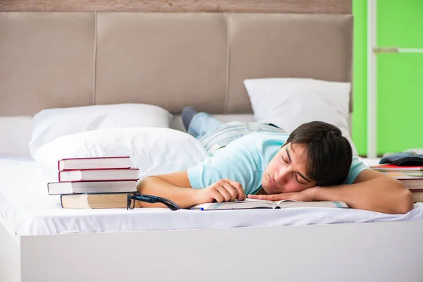 Студент готовился к экзаменам дома, в спальне, лежа на кровати — стоковое фото