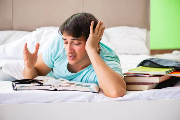 Studente che si prepara per gli esami a casa in camera da letto sdraiato sul letto — Foto Stock