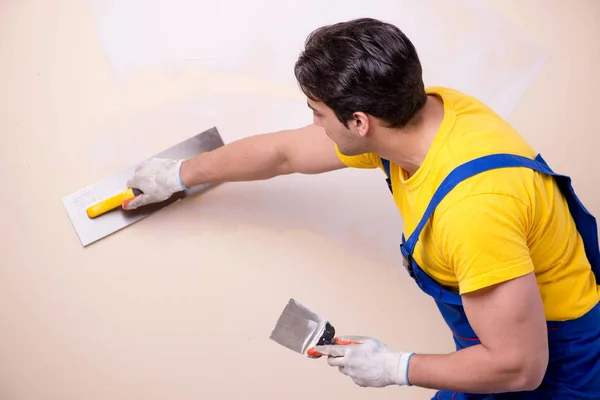 Empleado joven contratista aplicando yeso en la pared — Foto de Stock