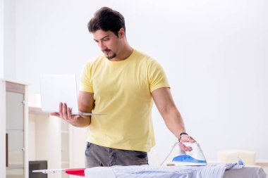 Yakışıklı koca evde kıyafet ütülüyor.