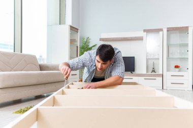 Adam evde mobilya montajı yapıyor.