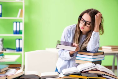 Sınavlara bir sürü kitapla hazırlanan genç kız öğrenci. 