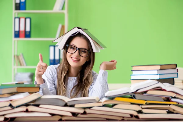 Jonge vrouwelijke student bereidt zich voor op examens met veel boeken — Stockfoto