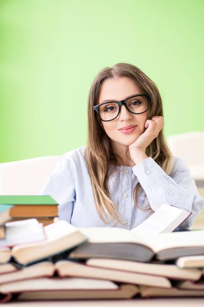 Jonge vrouwelijke student bereidt zich voor op examens met veel boeken — Stockfoto