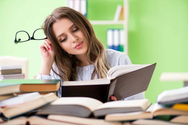 Jonge vrouwelijke student bereidt zich voor op examens met veel boeken — Stockfoto