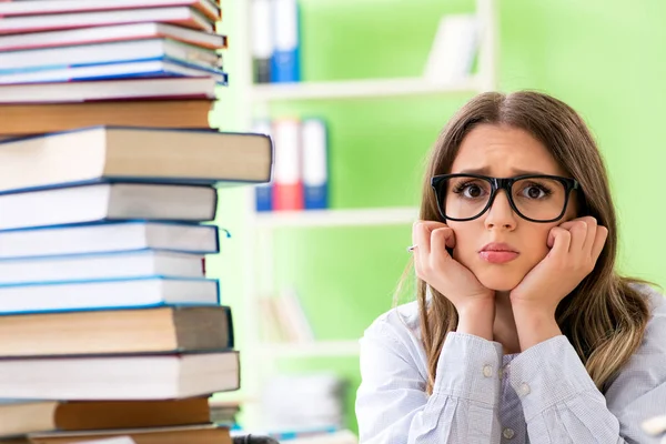 Jovem estudante se preparando para exames com muitos livros — Fotografia de Stock