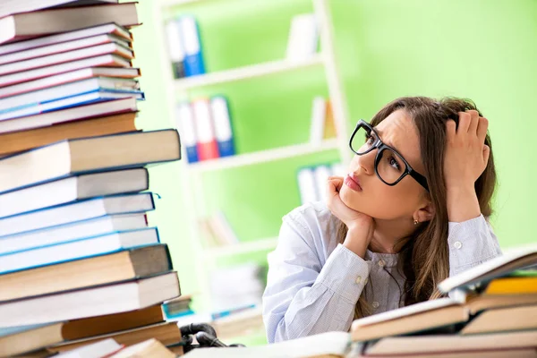 Jovem estudante se preparando para exames com muitos livros — Fotografia de Stock