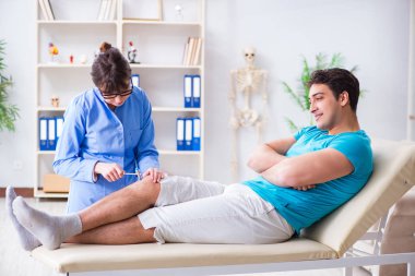 Doktor çekiçle sinir reflekslerini kontrol ediyor