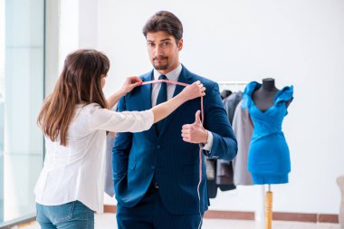Profesyonel terzi resmi kıyafet için ölçü alıyor.
