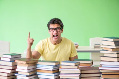 Sınavdan önce okumak için çok fazla kitabı olan öğrenci