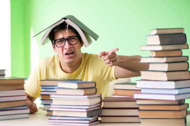 Sınavdan önce okumak için çok fazla kitabı olan öğrenci