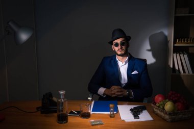 Dedektif karanlık odada klasik bir konseptle oturuyor.