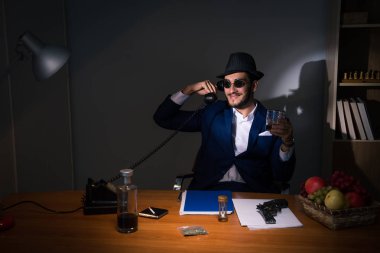 Dedektif karanlık odada klasik bir konseptle oturuyor.