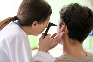 Tıbbi muayene sırasında kadın doktor hastaların kulaklarını kontrol ediyor. 