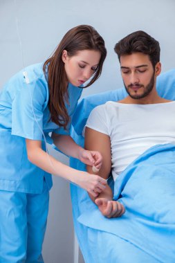 Kadın doktor erkek hastayı hastanede muayene ediyor.