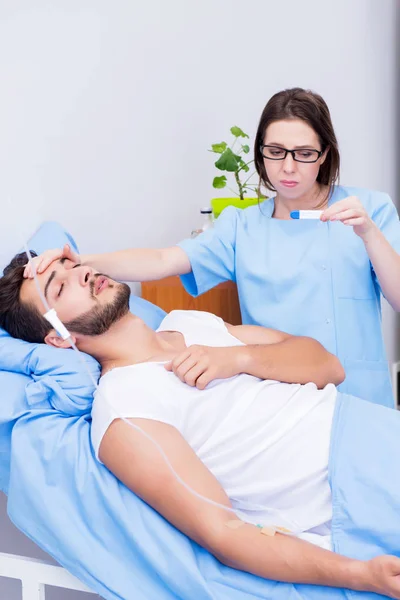 Kvinde læge undersøger mandlige patient på hospitalet - Stock-foto