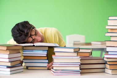 Sınavdan önce okumak için çok fazla kitabı olan öğrenci