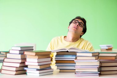 Sınavdan önce okumak için çok fazla kitabı olan öğrenci