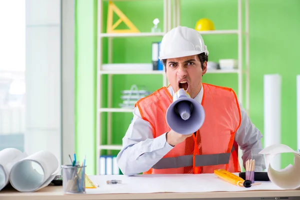 Construction supervisor with loudspeaker sitting in the office